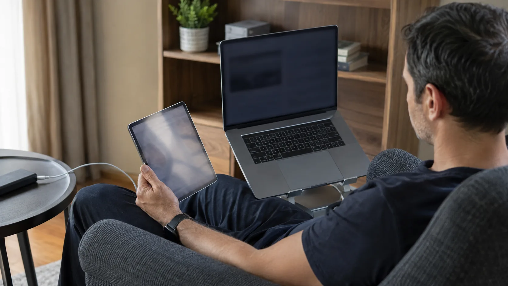 Adult comparing a tablet and laptop at home with both screens safely out of view